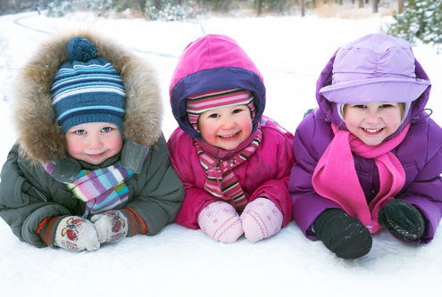 Group of children playing on snow in winter time