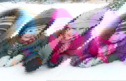 Group of children playing on snow in winter time