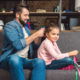 smiling father braiding his smiling daughters hair on the sofa as she plays with ribbons