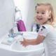 smiling happy toddler washing her hands at a bathroom sink