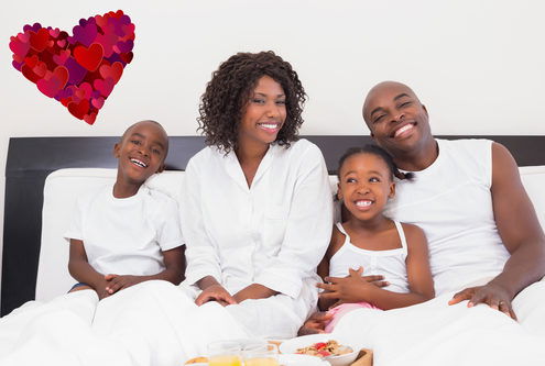 Happy family having breakfast in bed against heart