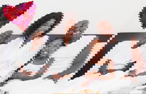 Happy family having breakfast in bed against heart