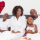 Happy family having breakfast in bed against heart
