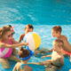 young kids playing with a beach ball in the pool