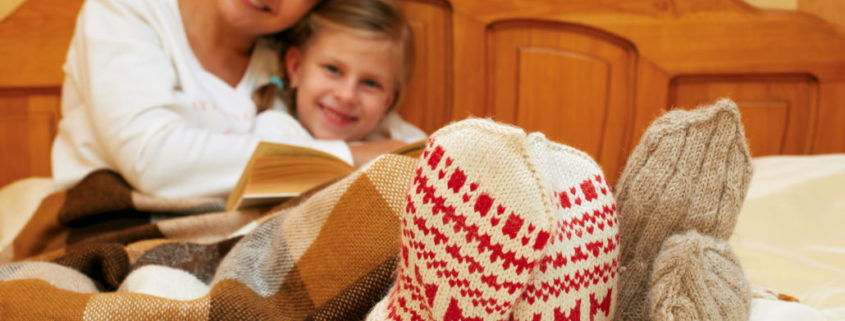 Mom and daughter lying on the bed in knitted socks reading