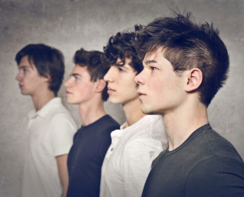 four teenage boys in a line waiting for their head lice screenings