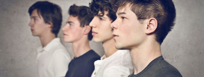 four teenage boys in a line waiting for their head lice screenings