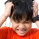 Little kid scratching their head making a irritated face because they have head lice