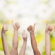 Bunch of arms raised in the air making the thumbs up with trees in the background