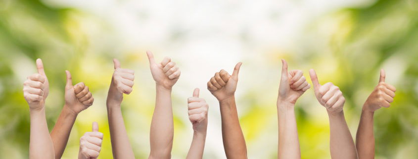 Bunch of arms raised in the air making the thumbs up with trees in the background