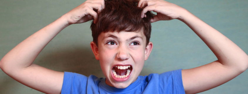 Young boy is upset he needs a head check because he may have lice wearing a blue t-shirt