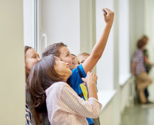 education, elementary school, drinks, children and people concept - group of school kids taking selfie with smartphone in corridor