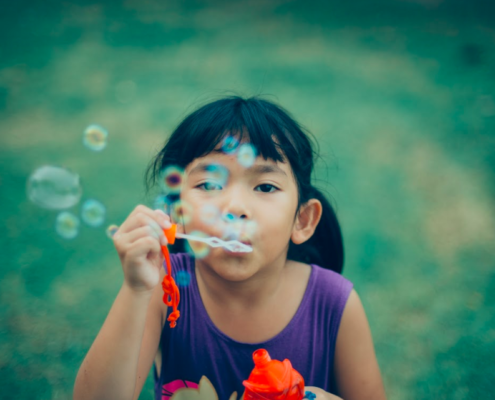 Young girl with bubbles at summer camp is happy she does not have lice because her parents followed summer lice prevention tips